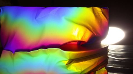 Showcase a captivating image featuring an iridescent gradient texture on a metallic surface.  The vibrant color shifts are en