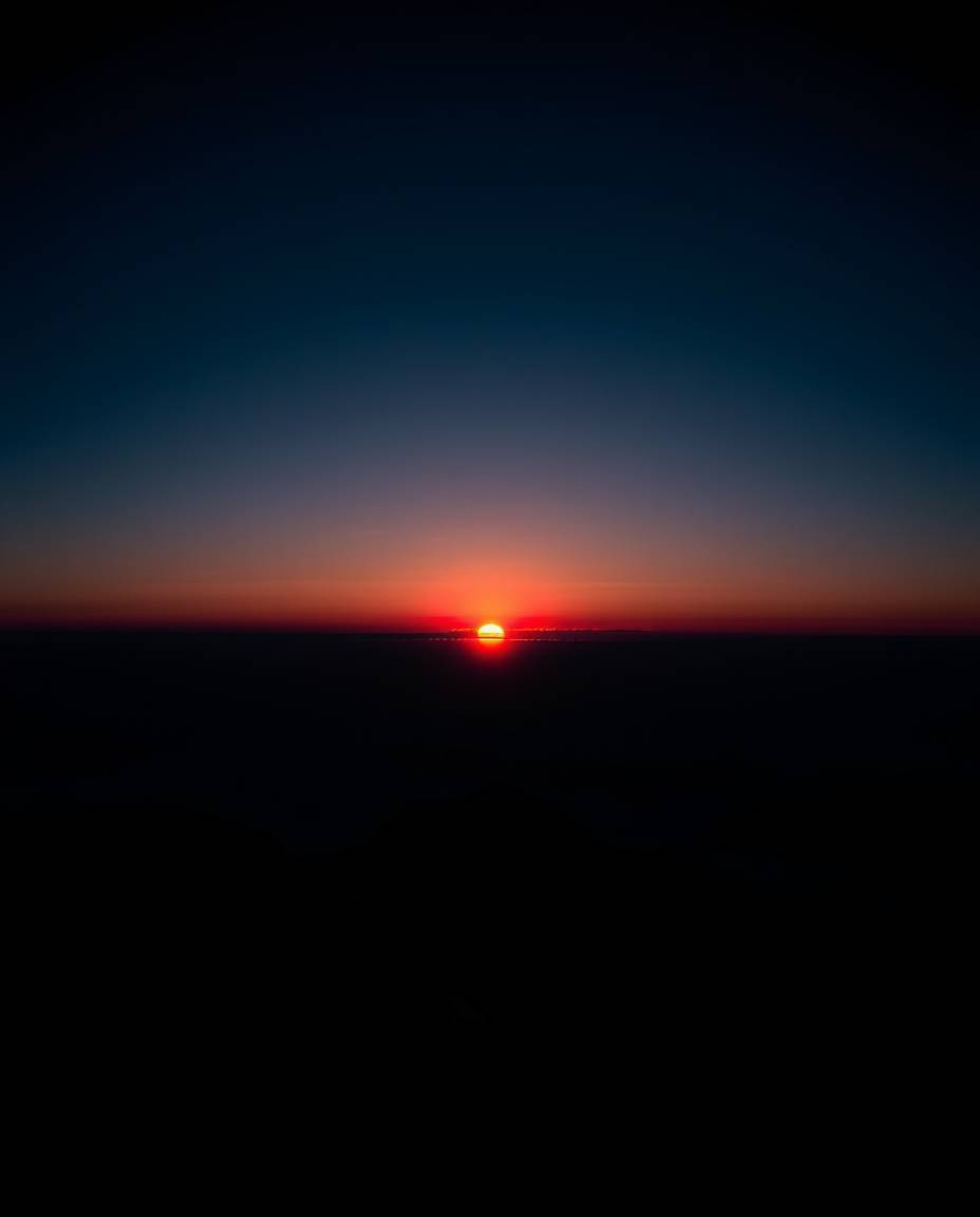 This is a high-contrast, low-key image capturing a sunset from a high alpine peak in a strong and moody style. The compositio