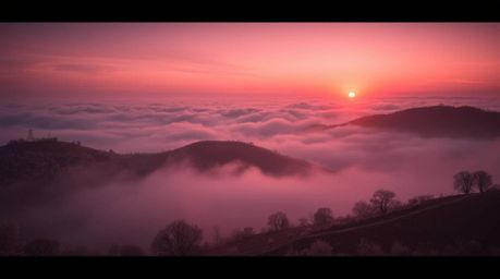 Experience the ethereal beauty of a surreal infrared photograph. This cinematic image captures fog-covered hills bathed in th