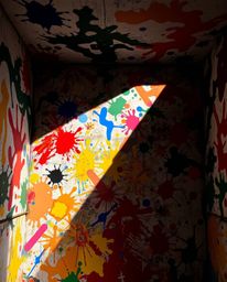 Experience the chaotic beauty of a room consumed by a vibrant paint explosion, captured from a unique split overhead bird's-e