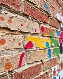 A stunning close-up captures vibrant graffiti-style splashes on a textured brick wall.  The image showcases a captivating ble