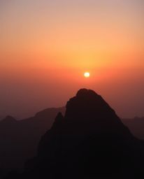 Experience a hazy sunset from a high alpine peak, where a soft, dreamy atmosphere meets dramatic lighting. This image feature