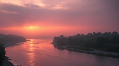 Capture the ethereal beauty of a winding river bathed in the warm glow of a dramatic orange-pink sunset. This soft, dreamy ph