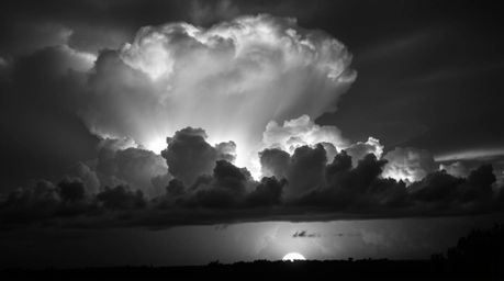 A captivating piece of creative light art depicts dramatic thunderstorm clouds brilliantly illuminated by the warm glow of a 