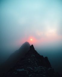 A soft cinematic haze envelops a sunset as viewed from a high alpine peak. This beautiful composition features warm terracott