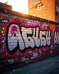 Capture the vibrant energy of street art with this stunning image.  Featuring graffiti-style colorful splashes on a brick wal