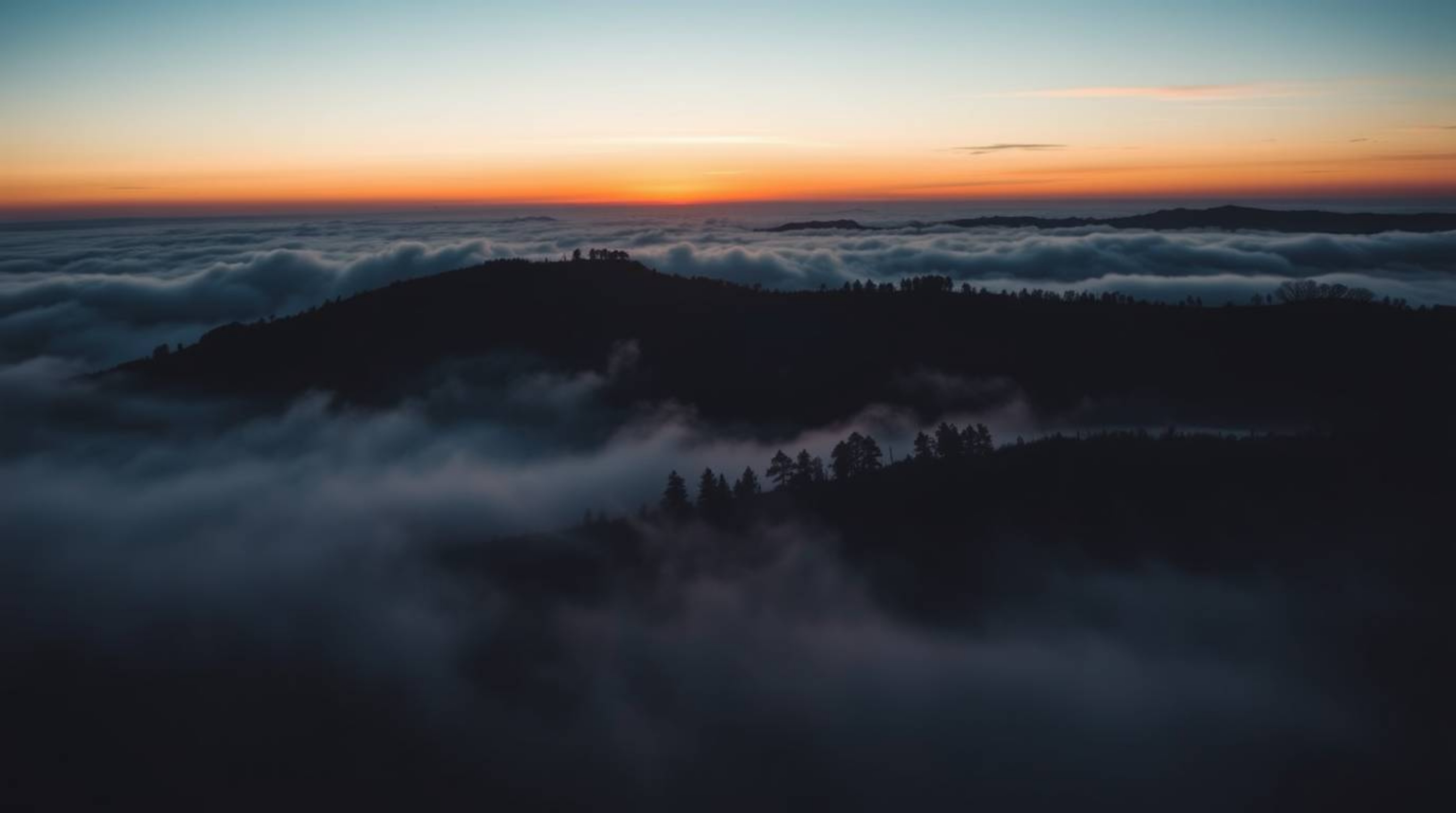 A breathtaking cinematic image captures fog-covered hills bathed in the warm glow of a setting sun.  The scene is dramaticall
