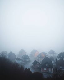 Discover a mesmerizing surreal watercolor painting of a sleepy town. Pastel-colored houses are shrouded in thick fog, creatin
