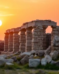 Capture a moment in time with this photograph of ancient stone ruins at sunset. A beautiful blurred bokeh effect creates a so
