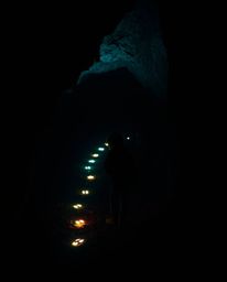 A child ventures into a dark cave, guided by a trail of eerie, glowing footsteps. The scene, rendered in unsettling details a