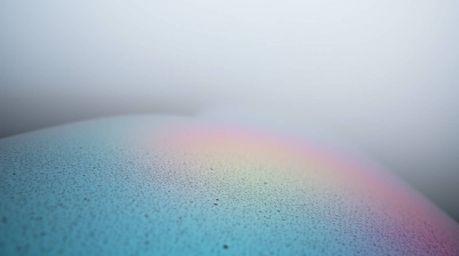 This captivating image features a tight close-up shot of an iridescent gradient texture on a metallic surface, showcasing vib
