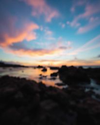 A candid street photography style image captures a colorful sky over a coral reef at low tide. Featuring a beautiful blurred 