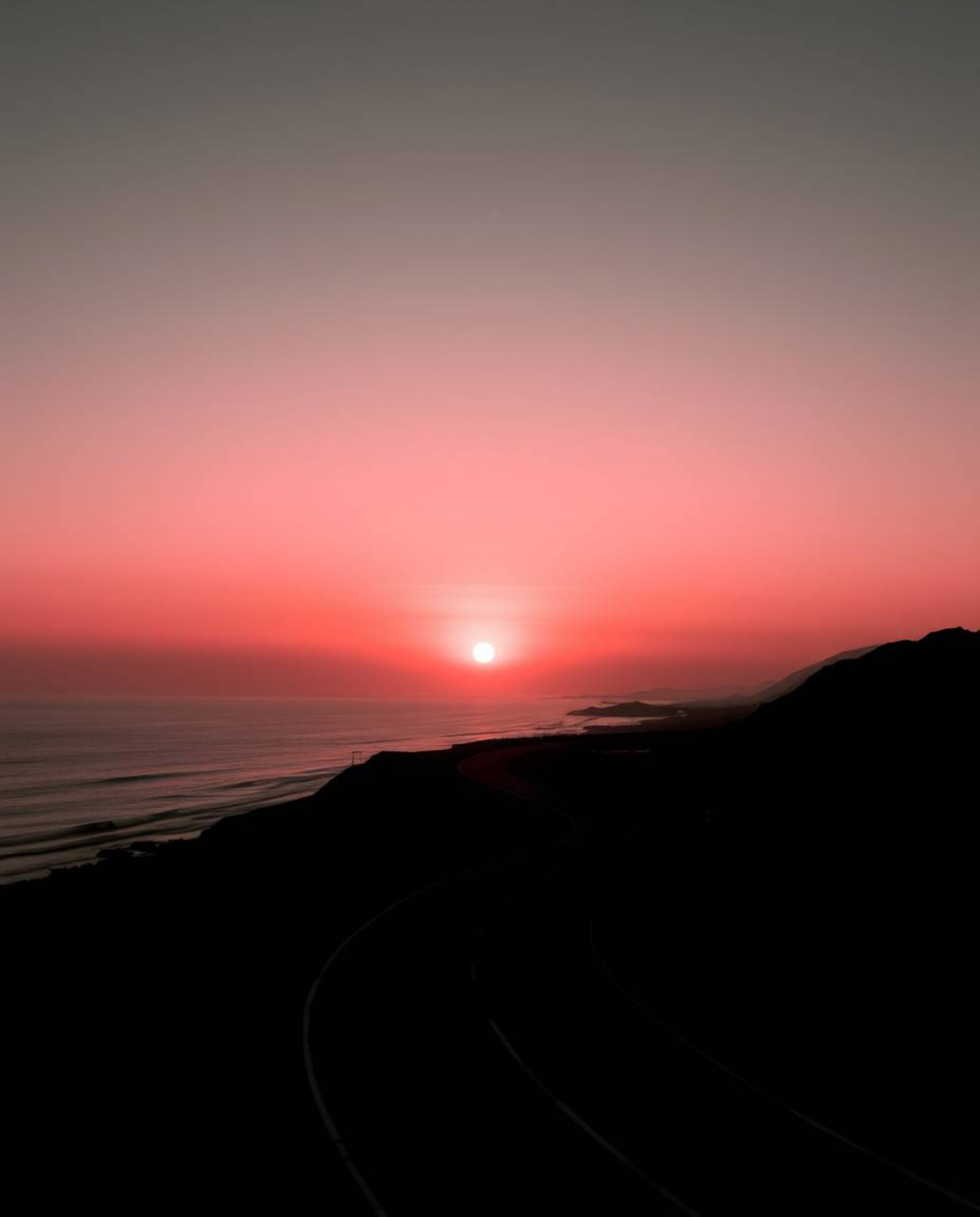 This is a graceful and elegant depiction of a sunset sky over a winding coastal highway. The artwork is rendered entirely in 