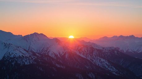 Experience the awe-inspiring beauty of snow-covered mountains illuminated by a pastel sunset in this striking image. The scen