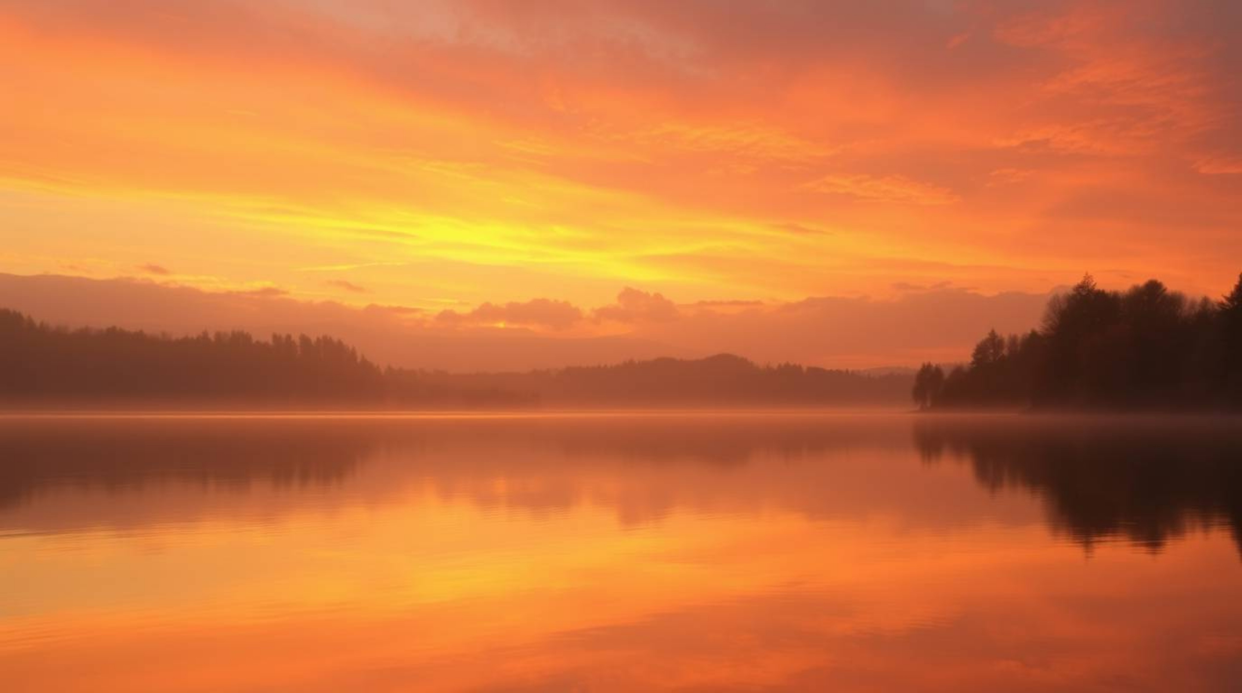 Experience the tranquility of a serene lake mirroring a vivid sunset sky, bathed in warm autumnal tones and gentle, soft ligh