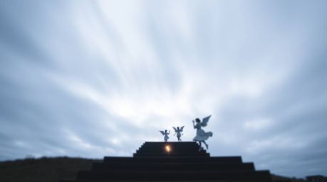 A long exposure photograph capturing steps of light ascending into a cloudy sky, with angelic figures silhouetted on the hori