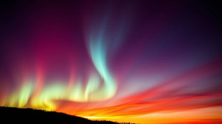 Experience the breathtaking beauty of the Northern Lights emerging over a vibrant sunset sky. This image showcases intense, d