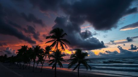 A captivating moody photograph depicting a tropical beach sunset.  Stormy skies create a high-tension atmosphere, contrasting