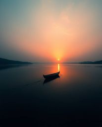 A high-contrast image, employing low-key lighting, showcases a boat adrift on a lake at sunset. This dramatic composition is 