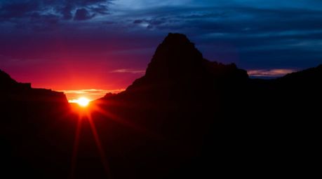 A stunning image of a rocky canyon silhouetted against a vibrant burgundy and deep blue sunset.  The backlighting creates a s