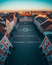 A striking overhead bird's-eye view depicting an empty town square, characterized by vibrant complementary colors, the subtle