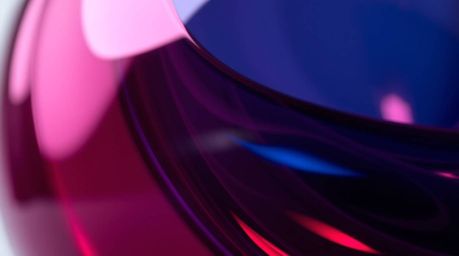 A close-up detail shot showcasing a glass object reflecting smooth gradient textures in rich burgundy and deep blue. The imag