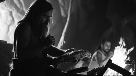 Experience a timeless scene with this classic black and white image depicting a caveman cooking mammoth meat.  The scene is i