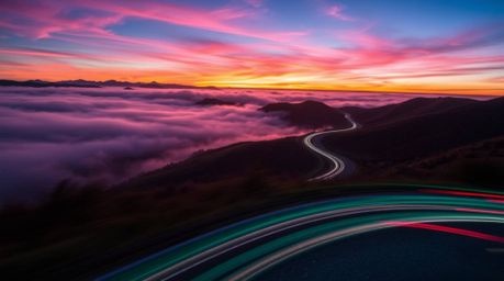 A captivating long-exposure photograph showcases vibrant electric colors painting the fog-covered hills at sunset.  Motion an