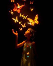 A captivating image showcases a girl releasing butterflies in a scene crafted with artistic lighting. The photograph features