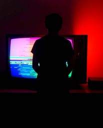 A retro-styled image showcasing a silhouetted figure dramatically backlit by a TV screen exhibiting RGB-separated glitch stat