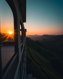 An architectural color photograph of a sunset over terraced tea plantations. The composition emphasizes sharp lines, detailed