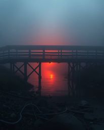 An extreme macro close-up captures the intricate details of an old wooden bridge over a river at sunset. The image is rendere