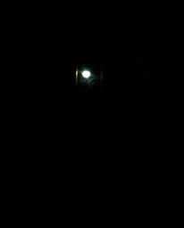 A surreal, dreamlike image captures intensely black eyes peering from the shadows of a dark alley at night. The scene is domi