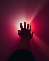 A captivating image depicting a hand reaching towards a bright light emerging from darkness.  The photograph showcases vibran