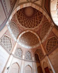 A precise architectural color photograph capturing the beauty of Islamic geometric patterns meticulously carved in stone. The