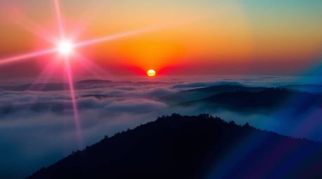 Experience the captivating beauty of fog-covered hills bathed in the warm glow of sunset. This split-toned image features a v