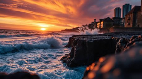 Capture the raw beauty of bioluminescent waves crashing against dramatic cliffs under a blazing sunset sky with extreme macro