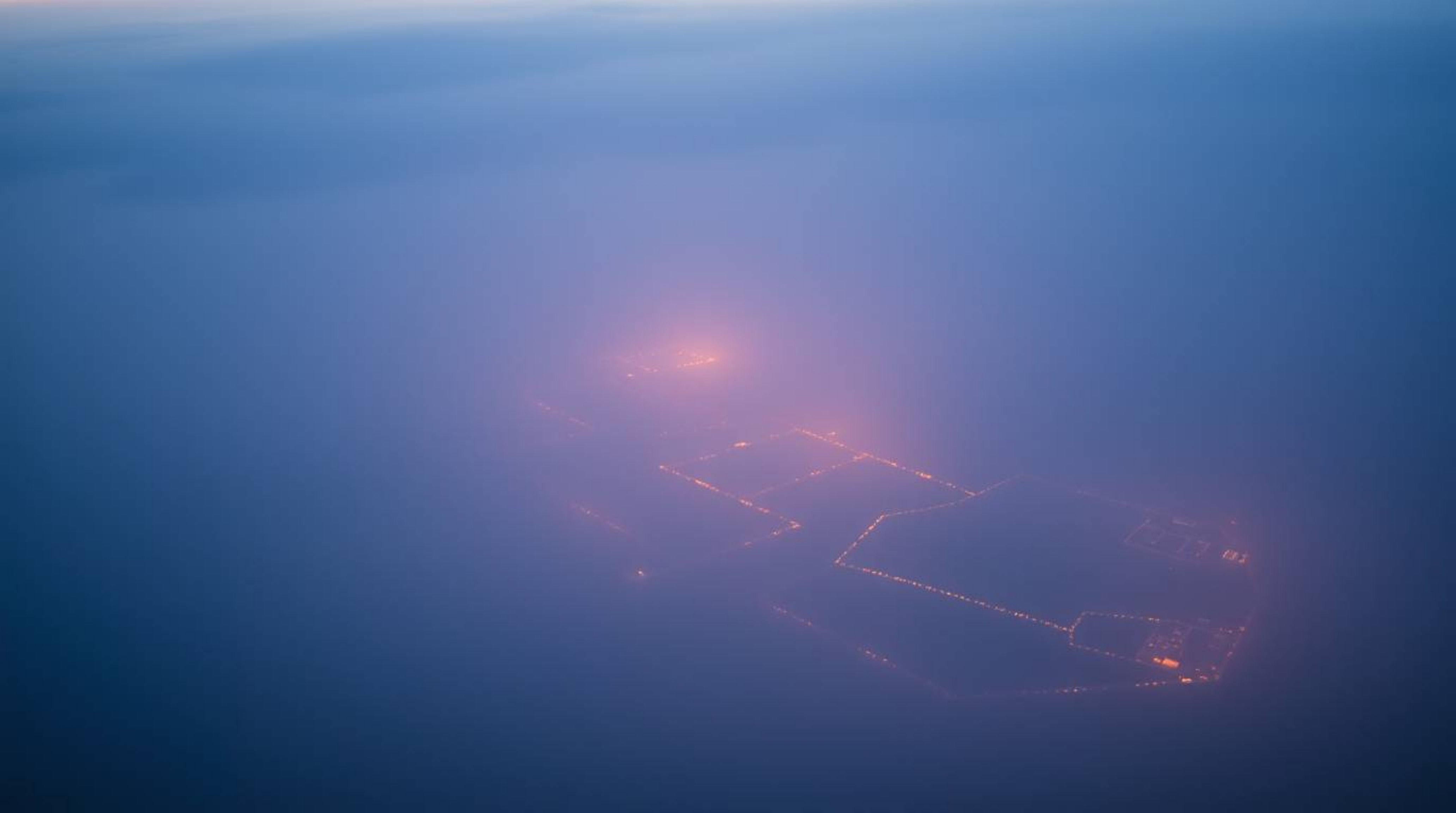 A tight close-up shot captures a river delta bathed in the ethereal glow of twilight colors, the thick fog enveloping the sur