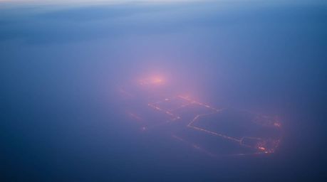 A tight close-up shot captures a river delta bathed in the ethereal glow of twilight colors, the thick fog enveloping the sur