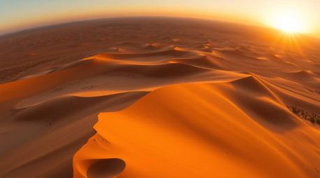 Capture the breathtaking beauty of a desert sunset with this high-angle perspective showcasing golden dunes stretching toward