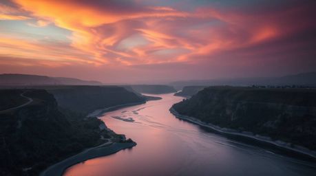 Capture the ethereal beauty of a winding river bathed in the radiant glow of a dramatic orange-pink sky. This fine art photog