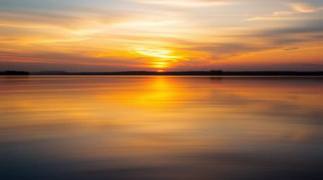 A captivating image showcases a serene lake mirroring a vibrant sunset sky.  The scene features smooth color gradients, subtl