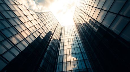 A modern glass building seamlessly blends into the sky in this striking high-angle perspective shot. Intense, dramatic lighti