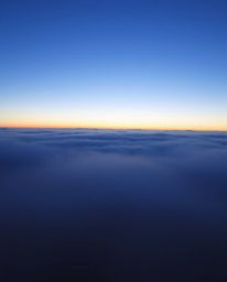 Witness a high-contrast sunset from a high alpine peak, where low visibility and thick fog create a mysterious and atmospheri