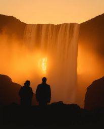 This artwork features silhouetted figures set against a dramatic waterfall as the sun sets behind it. The scene is dominated 