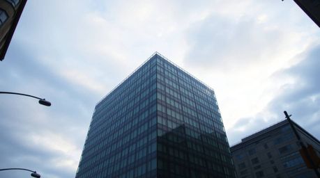 A captivating street photograph showcases a contemporary glass building seemingly dissolving into a serene sky painted with s