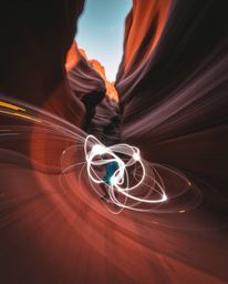 A work of creative light art captures a sunset illuminating sandstone canyon cliffs with dynamic motion. The piece is defined