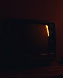 This high-contrast, low-key image features a mesmerizing TV screen glitch static with distinct RGB separation. The artwork in