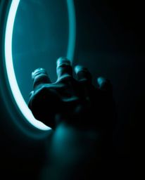 Explore a stunning macro close-up capturing a hand reaching from darkness towards a source of light, emphasizing vibrant elec