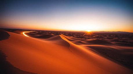 Experience the breathtaking beauty of a high-angle, long-exposure photograph capturing a vibrant sunset over golden desert du
